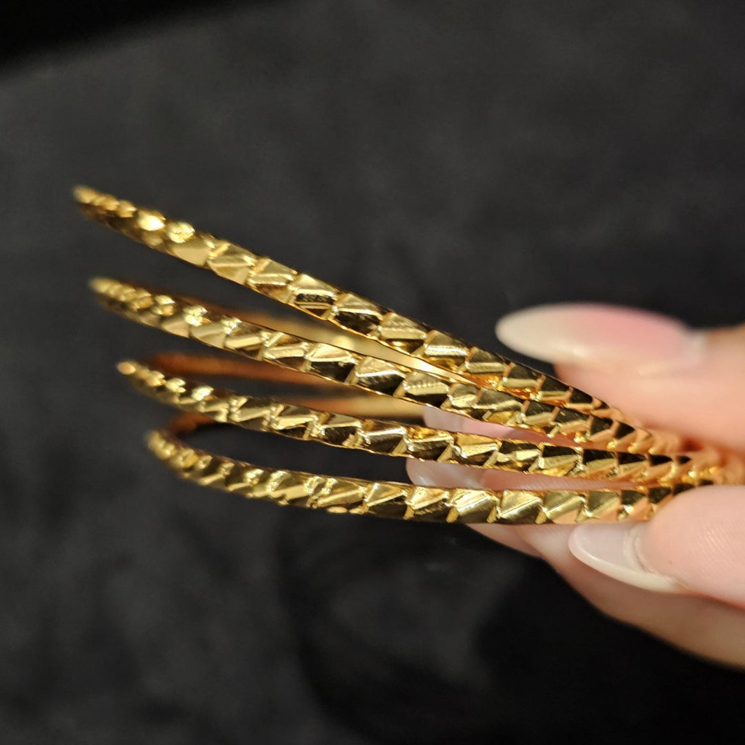 May include: Four gold bangles with a textured diamond pattern.