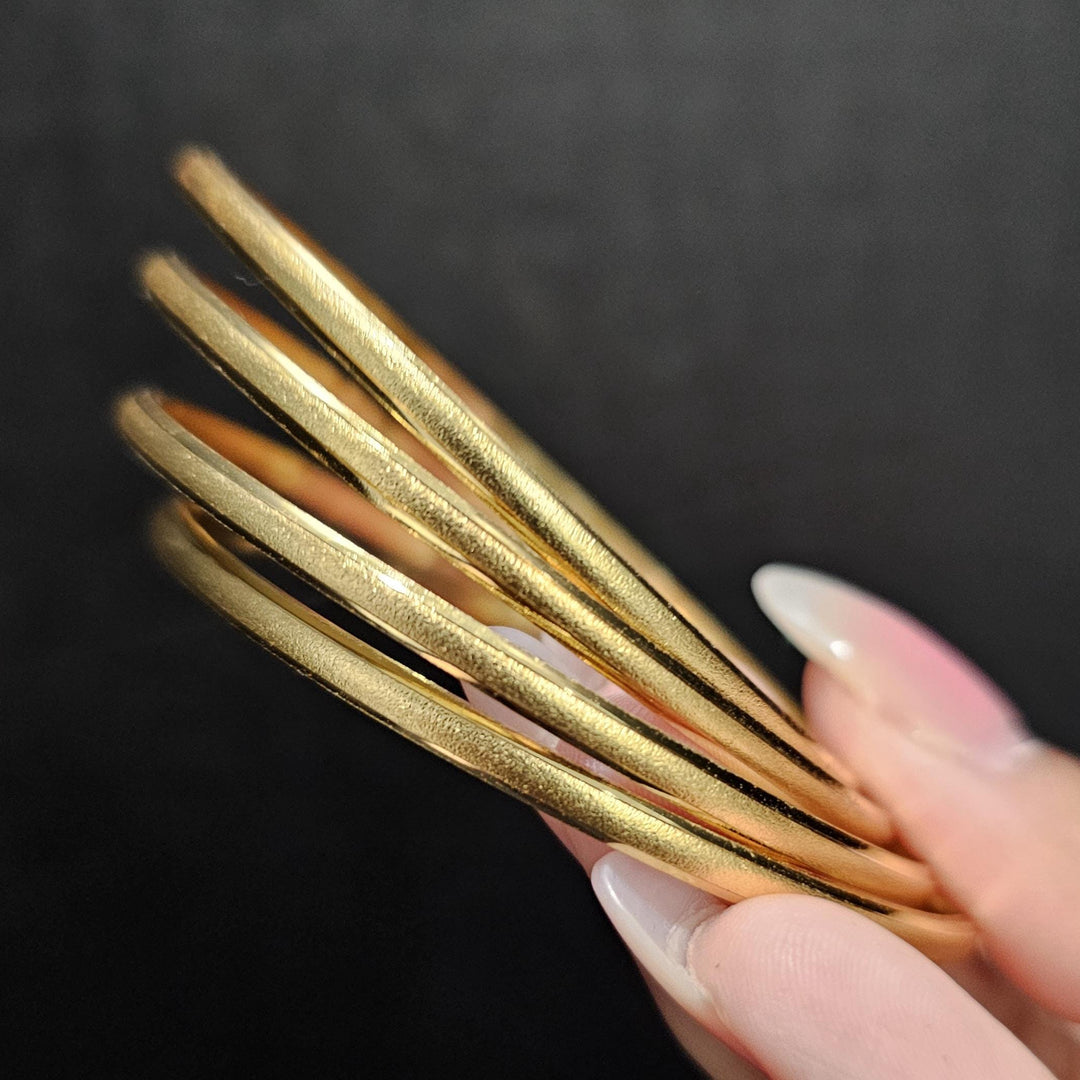 May include: Four gold bangles stacked together